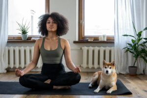 a woman with a dog on a mat in an apartment depicting dog-friendly yoga in NYC